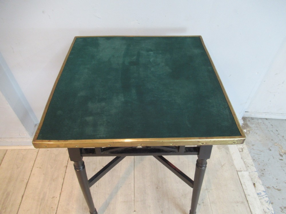 An antique ebonised occasional table featuring a square top with a green velvet insert and a brass border, supported by turned legs and cross-stretchers. View III