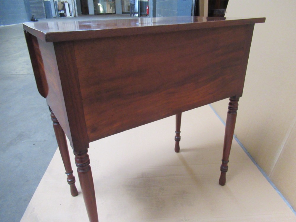 A Victorian mahogany side table featuring a drop-front door revealing an internal compartment with slatted support and turned wooden legs. View VI