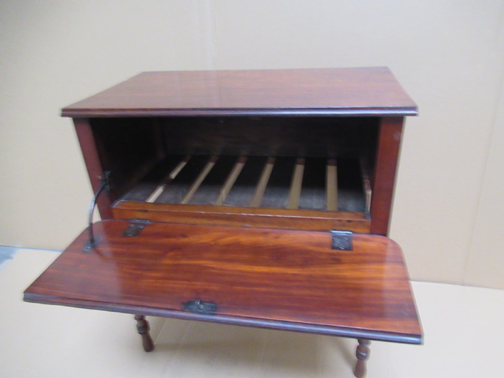 A Victorian mahogany side table featuring a drop-front door revealing an internal compartment with slatted support and turned wooden legs. View VII