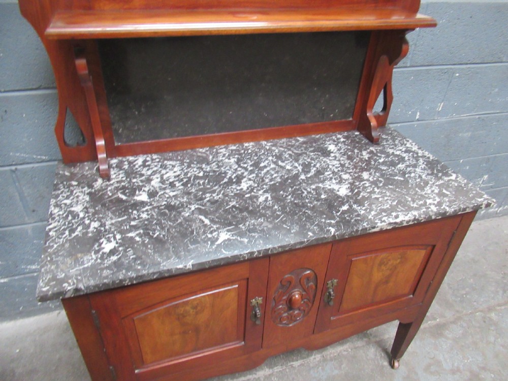 An Edwardian walnut washstand featuring a grey mottled marble top, double cupboards with burr walnut panels, and an oval mirror superstructure. View V
