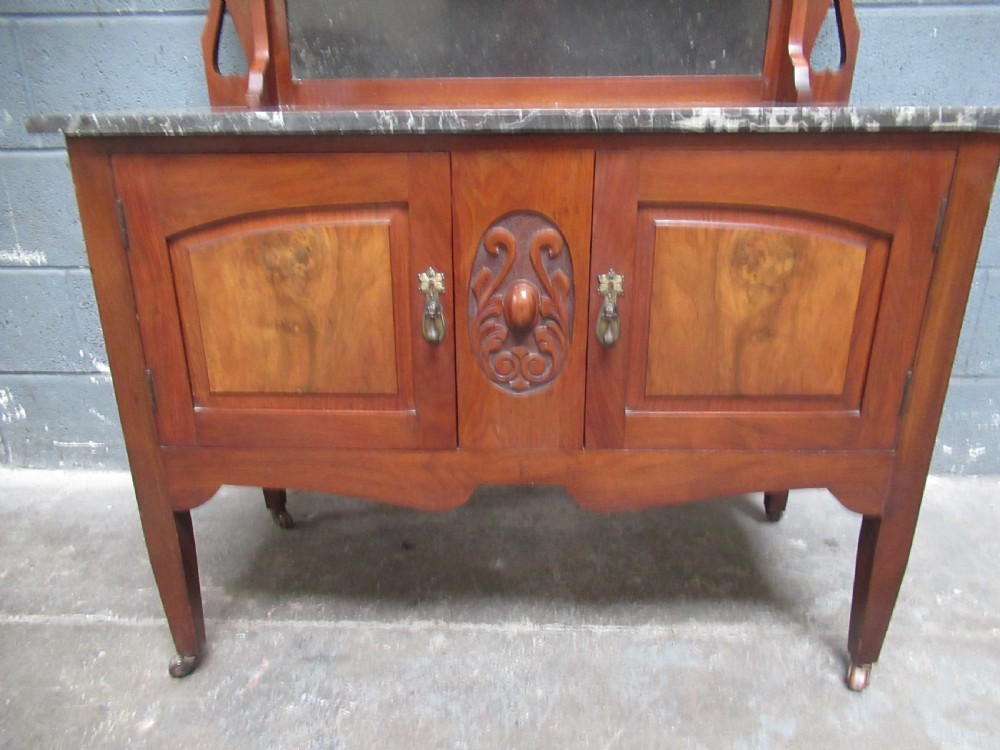 An Edwardian walnut washstand featuring a grey mottled marble top, double cupboards with burr walnut panels, and an oval mirror superstructure. View VI