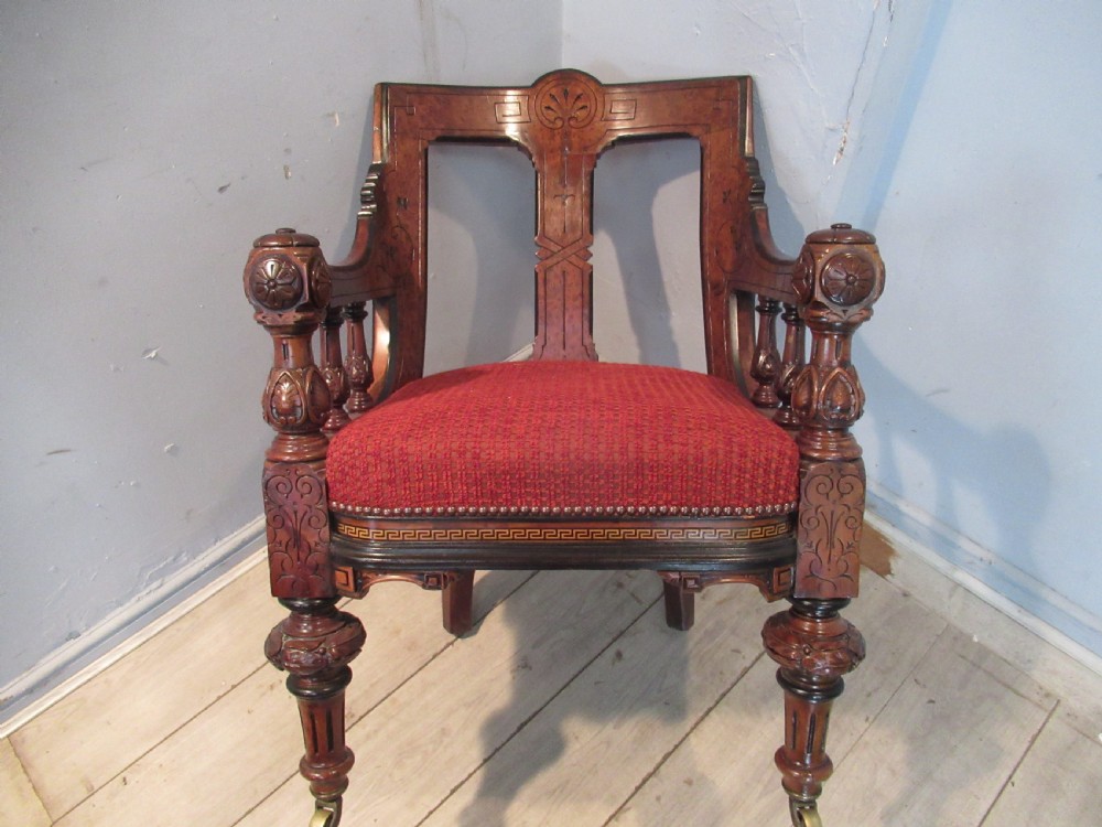 A set of three Victorian mahogany open armchairs with carved backrests, red upholstered seats, and turned front legs on brass castors. View IV