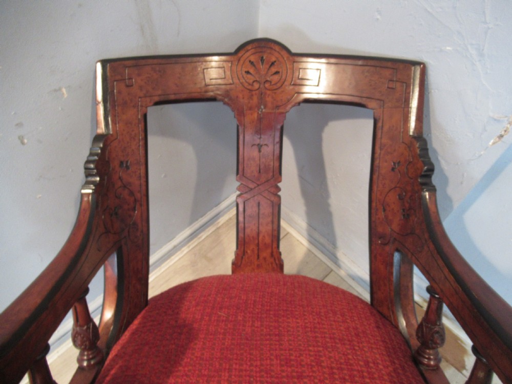 A set of three Victorian mahogany open armchairs with carved backrests, red upholstered seats, and turned front legs on brass castors. View IX