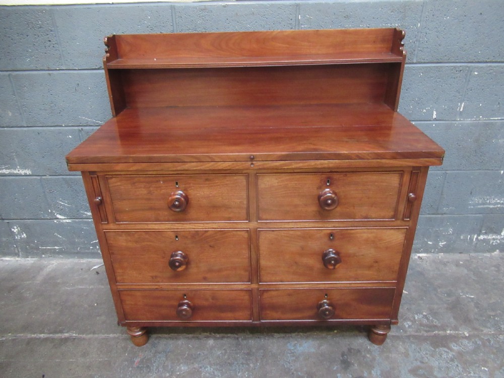 A Victorian mahogany chest of drawers featuring a fold-out top surface, an upper open shelf gallery, and turned wooden knobs. View II