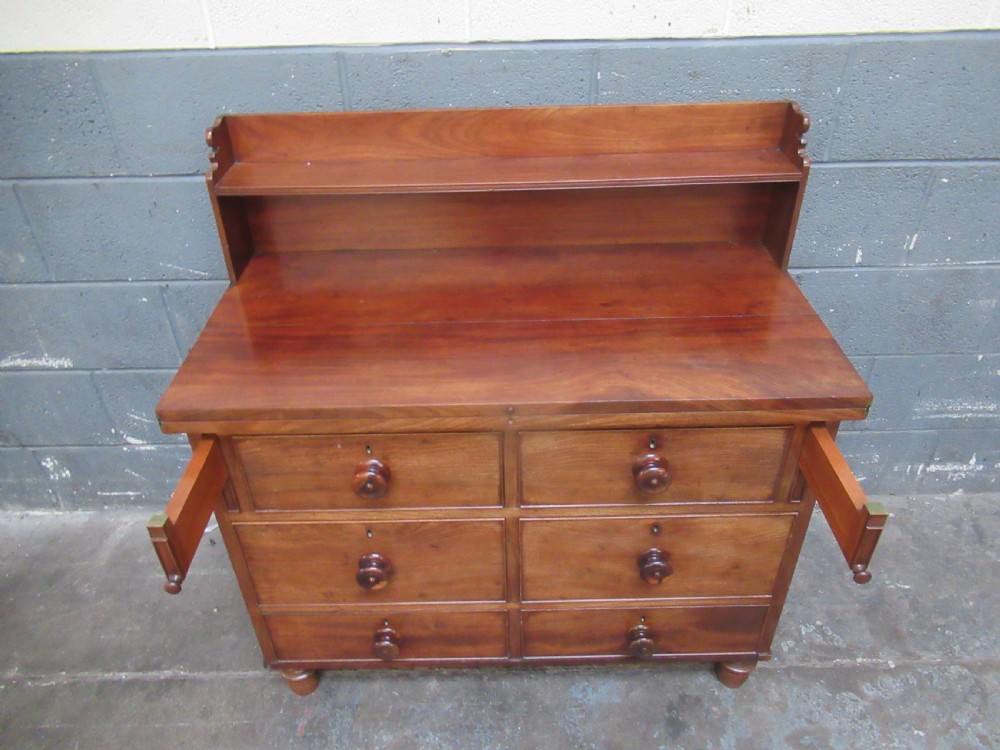 A Victorian mahogany chest of drawers featuring a fold-out top surface, an upper open shelf gallery, and turned wooden knobs. View VII
