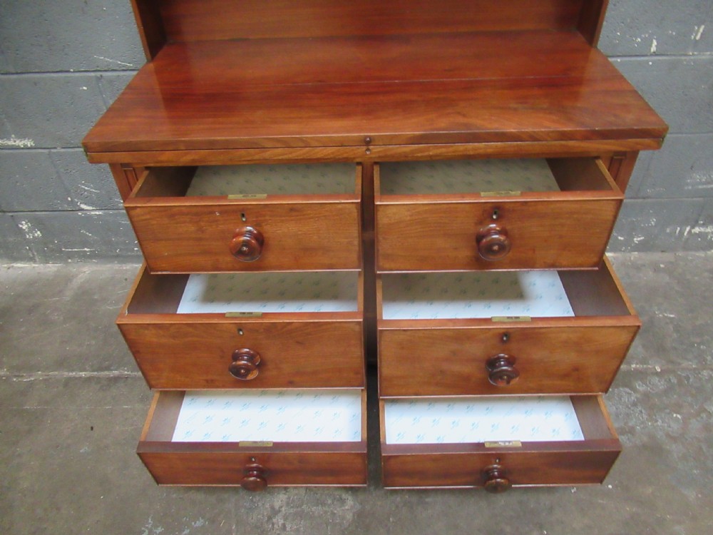 A Victorian mahogany chest of drawers featuring a fold-out top surface, an upper open shelf gallery, and turned wooden knobs. View VIII