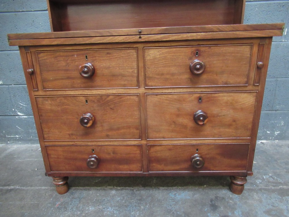 A Victorian mahogany chest of drawers featuring a fold-out top surface, an upper open shelf gallery, and turned wooden knobs. View X