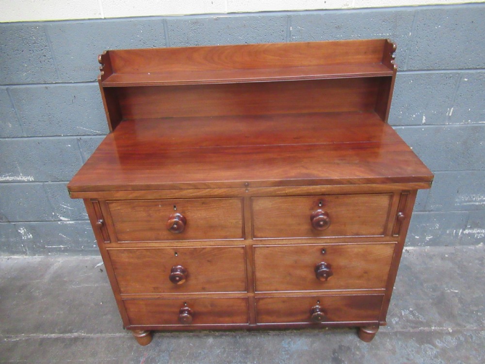 A Victorian mahogany chest of drawers featuring a fold-out top surface, an upper open shelf gallery, and turned wooden knobs. View XII