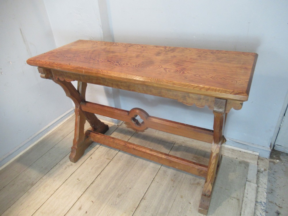 A Victorian pitch pine side table with a rectangular top, scalloped apron, and trestle supports joined by a stretcher with a carved quatrefoil motif. View V