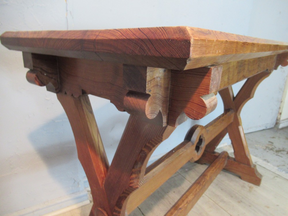 A Victorian pitch pine side table with a rectangular top, scalloped apron, and trestle supports joined by a stretcher with a carved quatrefoil motif. View X