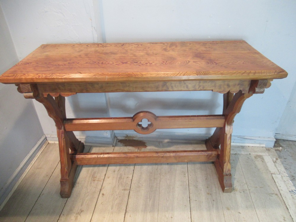 A Victorian pitch pine side table with a rectangular top, scalloped apron, and trestle supports joined by a stretcher with a carved quatrefoil motif. View XIII