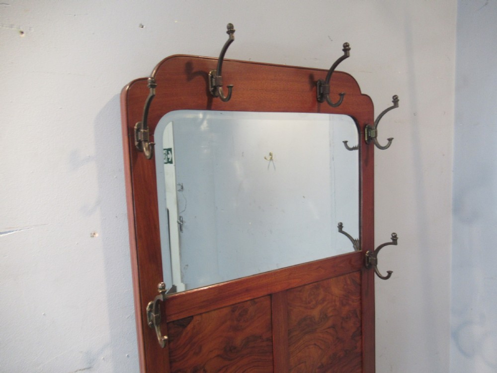 An antique walnut hall stand featuring an integrated mirror, multiple brass coat hooks, a central glove box, and a lower umbrella rack with metal drip trays. View II