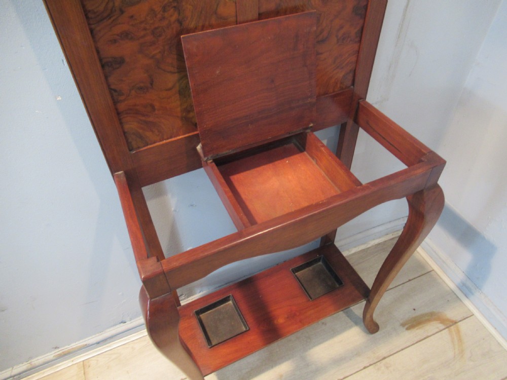 An antique walnut hall stand featuring an integrated mirror, multiple brass coat hooks, a central glove box, and a lower umbrella rack with metal drip trays. View V