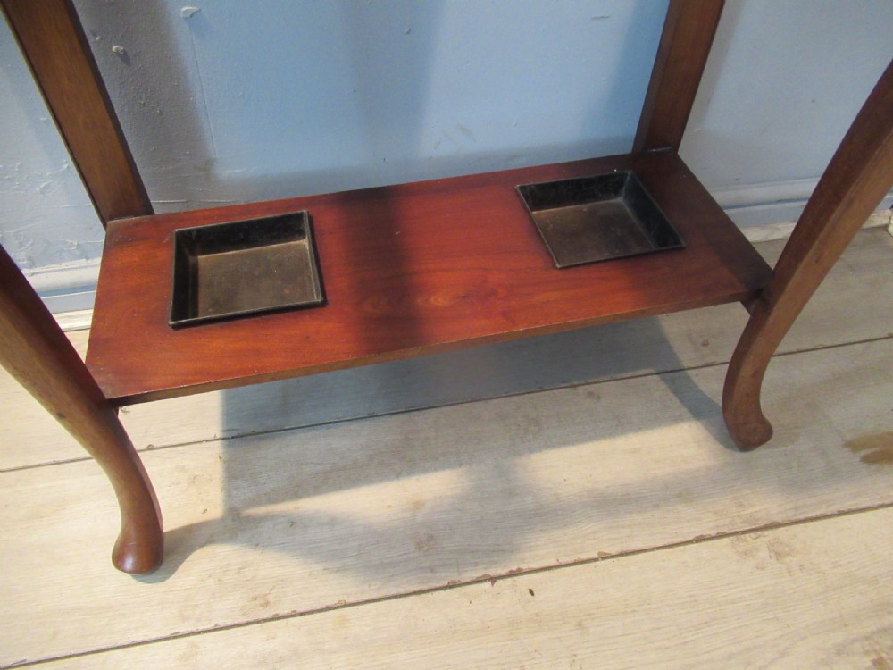 An antique walnut hall stand featuring an integrated mirror, multiple brass coat hooks, a central glove box, and a lower umbrella rack with metal drip trays. View VII