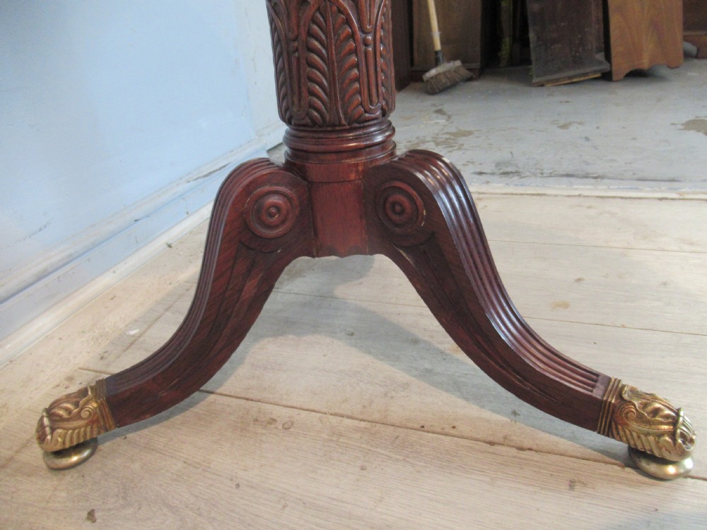 A Regency period circular table featuring a white marble top supported by a reeded mahogany pedestal on a splayed tripod base with brass feet. View V