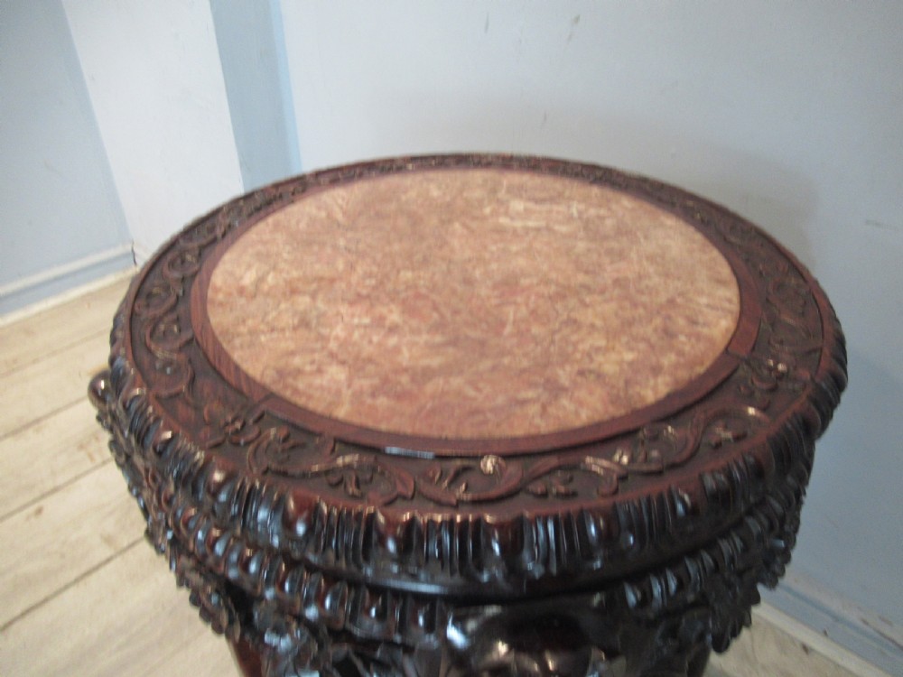 A circular dark carved hardwood side table featuring an inset marble top, pierced floral apron, lower tier shelf, and legs terminating in claw feet. View VIII
