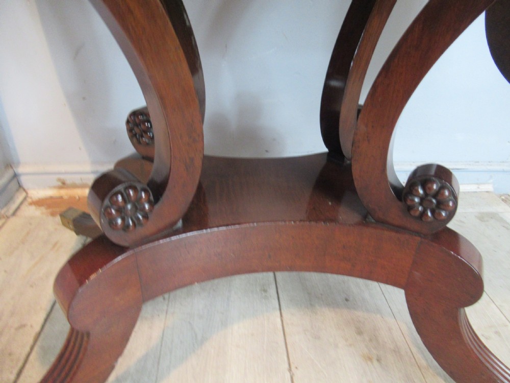 An early 19th-century mahogany sofa table featuring two drop leaf flaps, two front drawers with brass handles, twin scroll supports, and reeded legs with brass castors. View VII