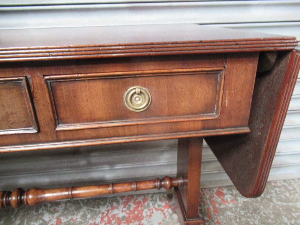 A mahogany sofa table featuring drop-leaf sides, front drawers with brass ring handles, a turned stretcher, and splayed sabre legs with brass castors. View III