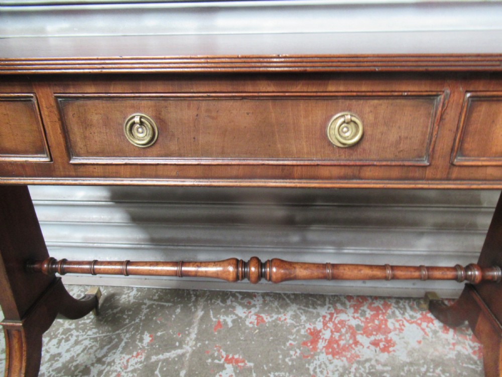 A mahogany sofa table featuring drop-leaf sides, front drawers with brass ring handles, a turned stretcher, and splayed sabre legs with brass castors. View V