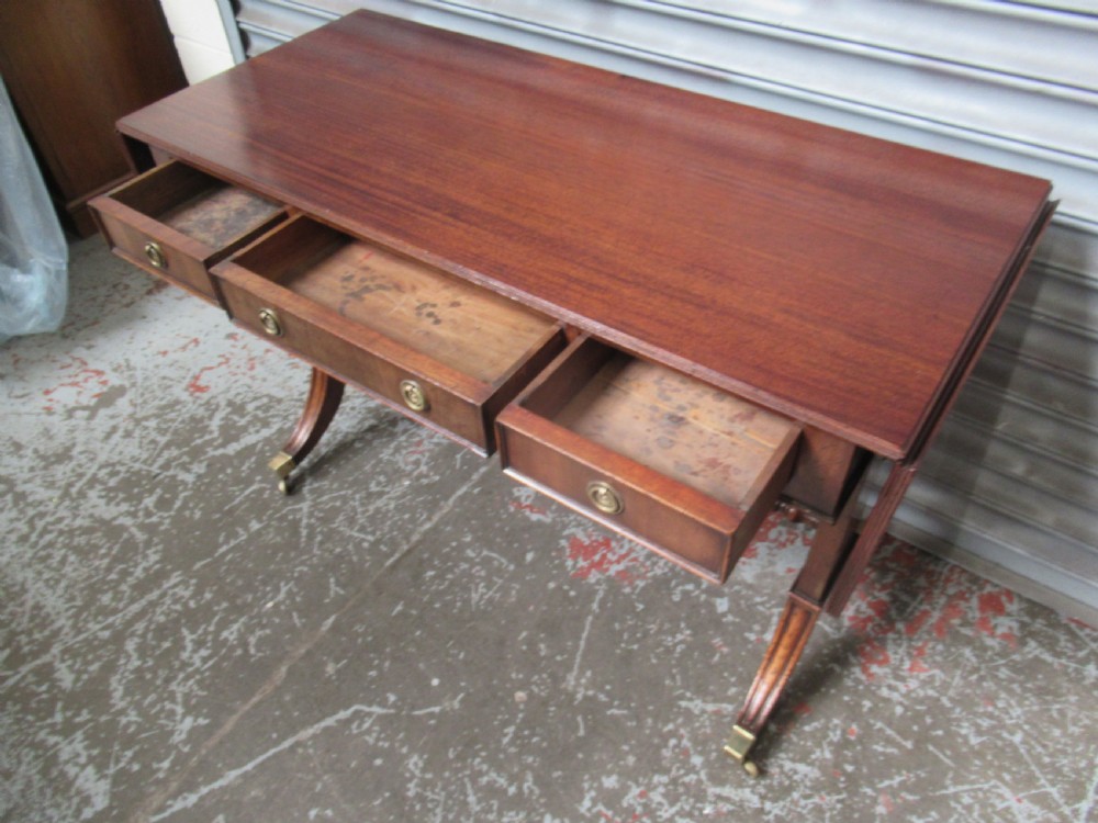 A mahogany sofa table featuring drop-leaf sides, front drawers with brass ring handles, a turned stretcher, and splayed sabre legs with brass castors. View VII