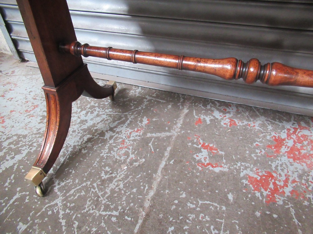 A mahogany sofa table featuring drop-leaf sides, front drawers with brass ring handles, a turned stretcher, and splayed sabre legs with brass castors. View X