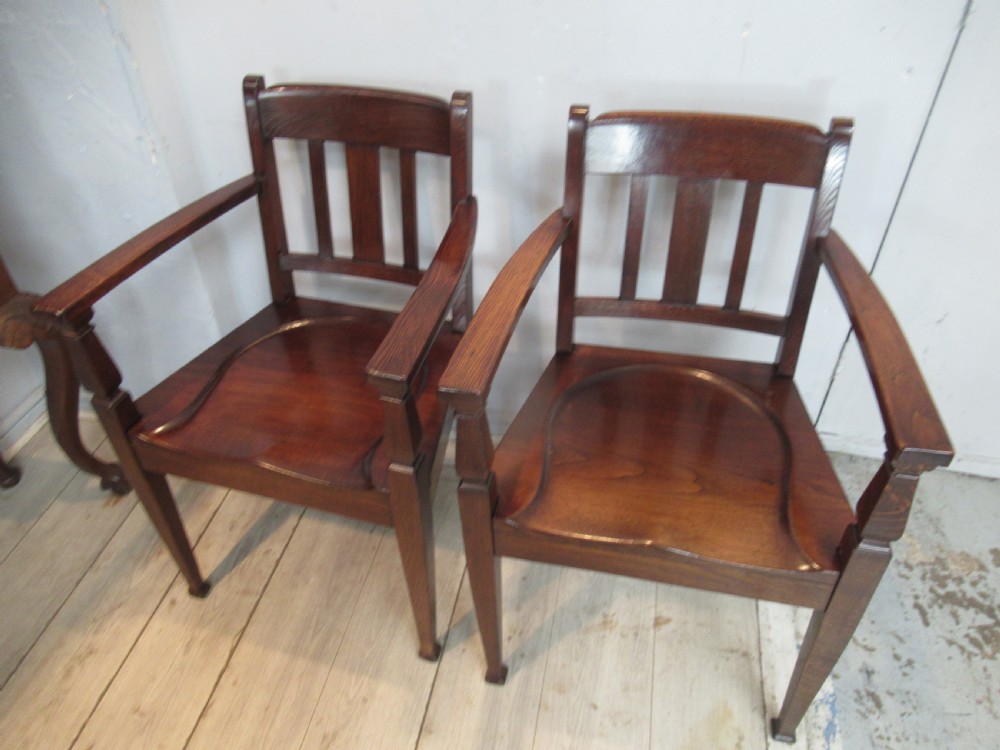 A pair of dark oak Arts and Crafts armchairs featuring vertical back slats, contoured solid timber seats, and straight tapered legs. View II