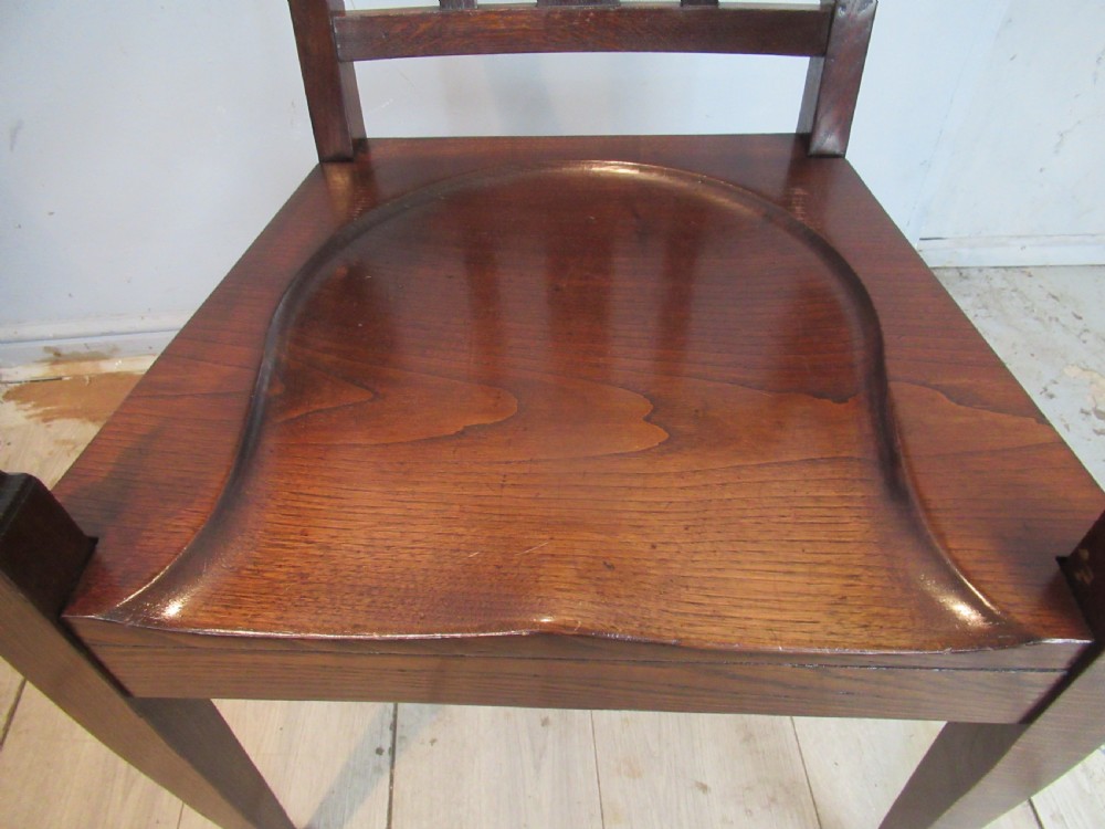 A pair of dark oak Arts and Crafts armchairs featuring vertical back slats, contoured solid timber seats, and straight tapered legs. View VII