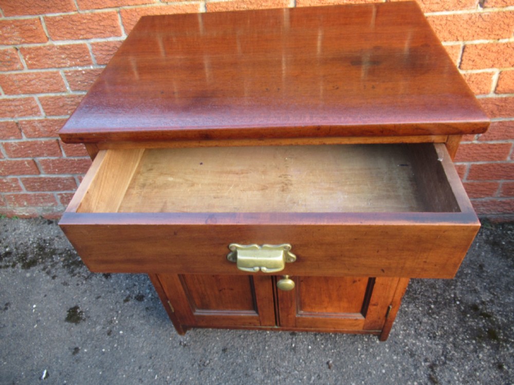 A small warm brown mahogany cupboard featuring a single top drawer with a brass cup handle and two panelled doors below with a brass knob. View IX