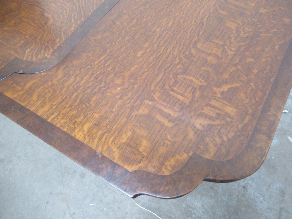 A dark carved oak extending dining table featuring ornate pedestal supports and a carved apron. View VII