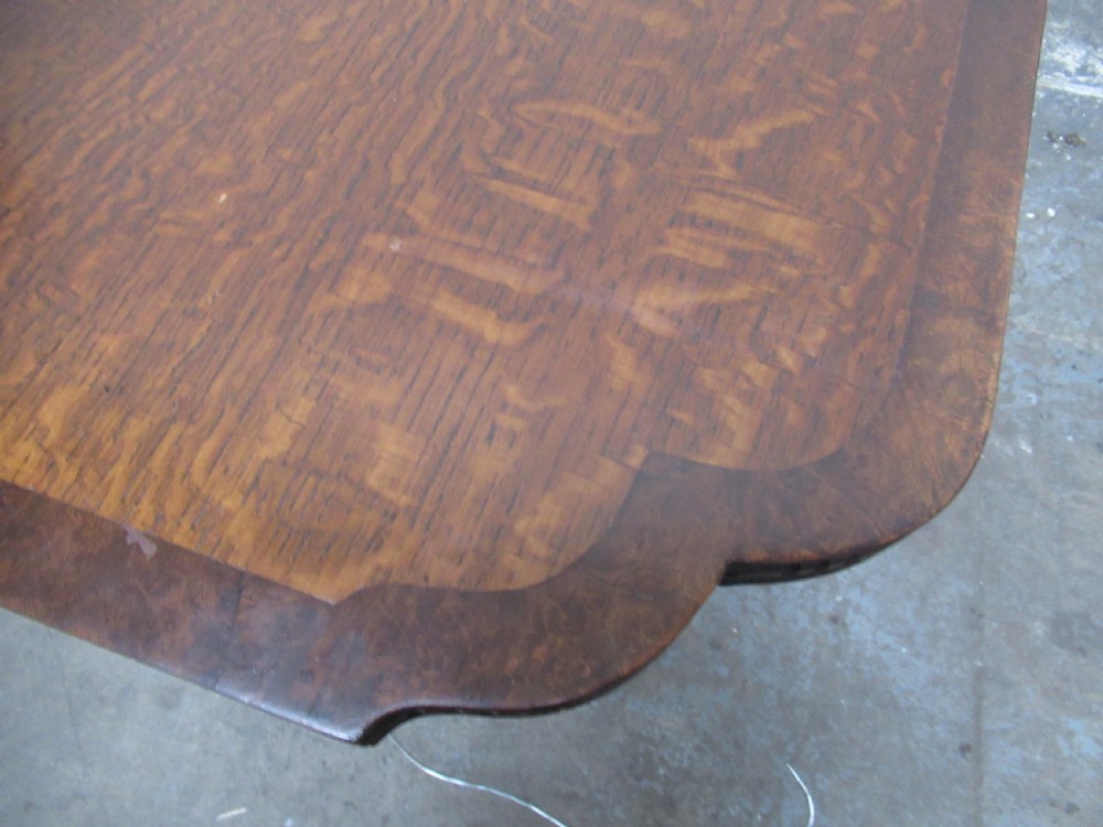 A dark carved oak extending dining table featuring ornate pedestal supports and a carved apron. View VIII