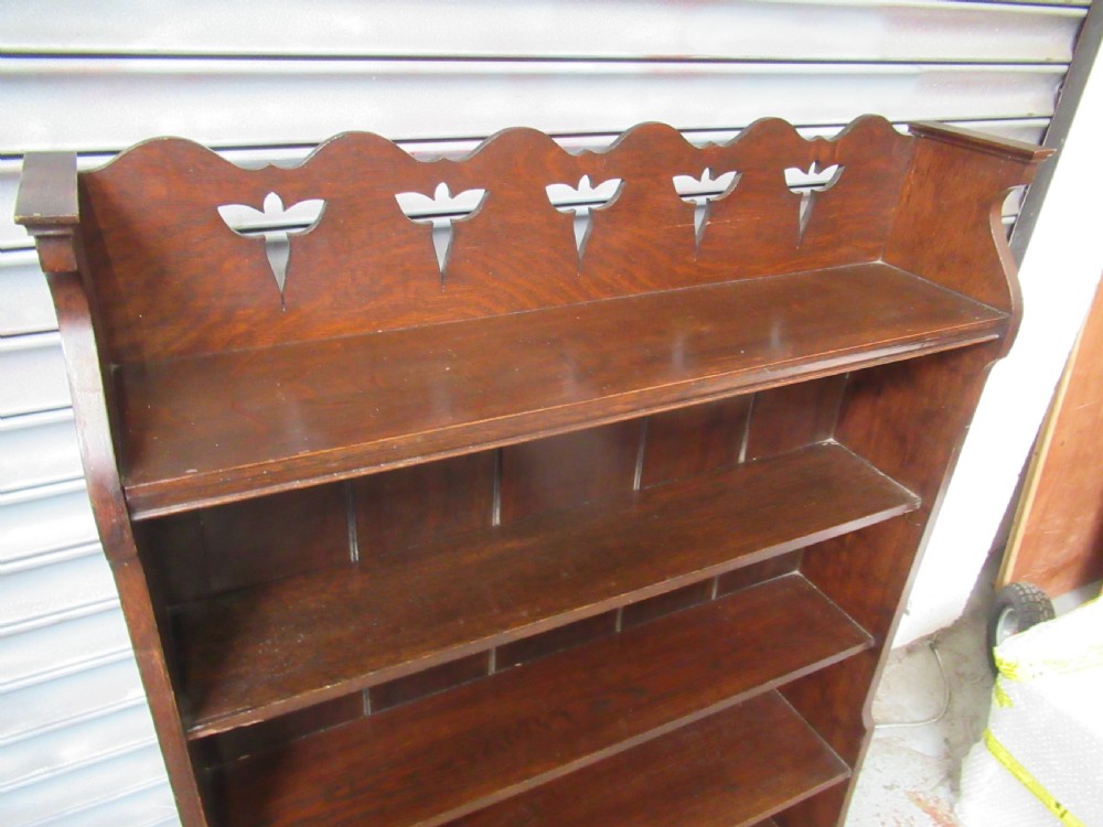 A tall dark oak open bookcase featuring four fixed shelves and a shaped gallery top decorated with pierced cut-outs. View II