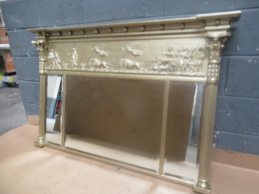 A 19th-century Regency gilt overmantel mirror featuring a detailed classical relief frieze, fluted side columns, and three glass mirror panels.