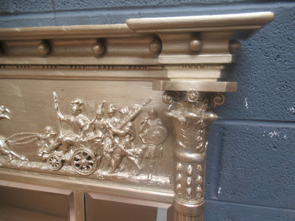 A 19th-century Regency gilt overmantel mirror featuring a detailed classical relief frieze, fluted side columns, and three glass mirror panels. View VI