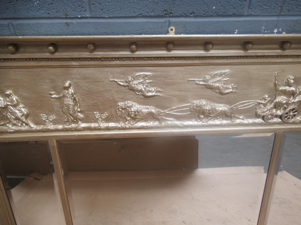 A 19th-century Regency gilt overmantel mirror featuring a detailed classical relief frieze, fluted side columns, and three glass mirror panels. View X