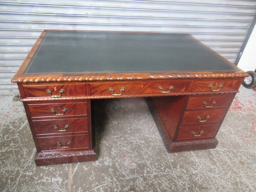 A large mahogany Georgian style pedestal desk featuring a dark green leather writing surface, brass swan-neck handles, and carved rope-twist moulding along the top edge.