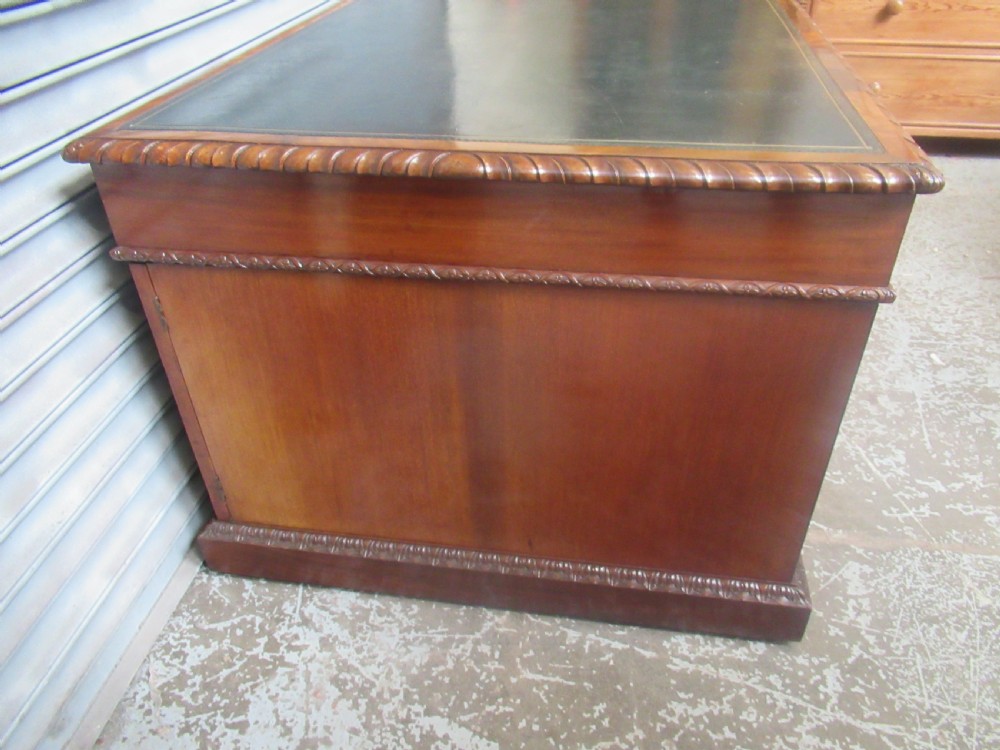 A large mahogany Georgian style pedestal desk featuring a dark green leather writing surface, brass swan-neck handles, and carved rope-twist moulding along the top edge. View III