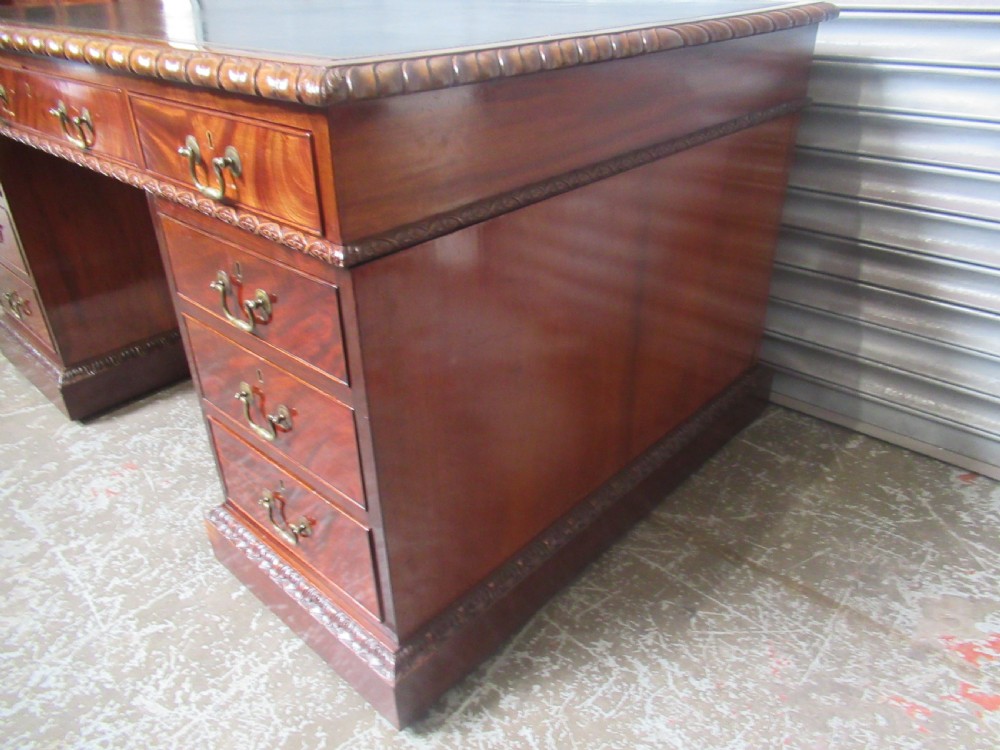 A large mahogany Georgian style pedestal desk featuring a dark green leather writing surface, brass swan-neck handles, and carved rope-twist moulding along the top edge. View V
