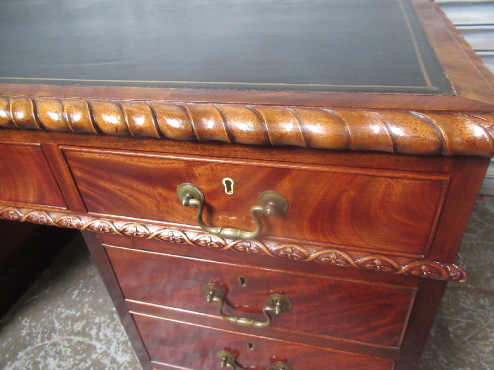 A large mahogany Georgian style pedestal desk featuring a dark green leather writing surface, brass swan-neck handles, and carved rope-twist moulding along the top edge. View VIII