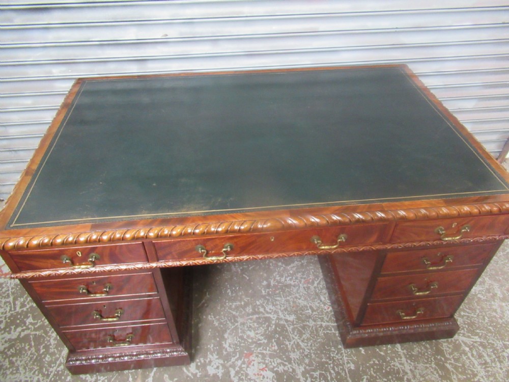 A large mahogany Georgian style pedestal desk featuring a dark green leather writing surface, brass swan-neck handles, and carved rope-twist moulding along the top edge. View XI