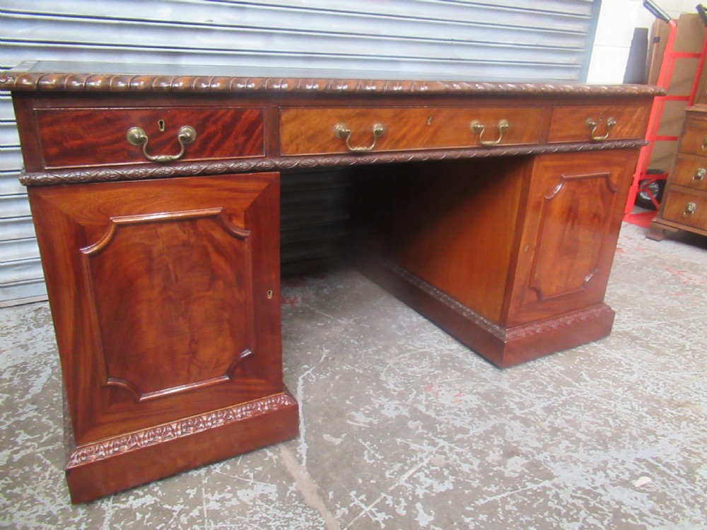A large mahogany Georgian style pedestal desk featuring a dark green leather writing surface, brass swan-neck handles, and carved rope-twist moulding along the top edge. View XVII