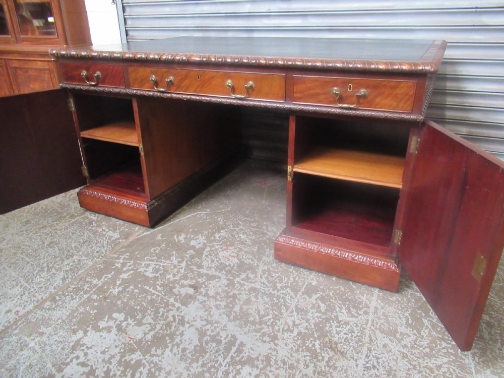 A large mahogany Georgian style pedestal desk featuring a dark green leather writing surface, brass swan-neck handles, and carved rope-twist moulding along the top edge. View XX