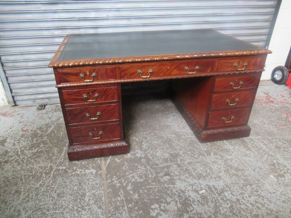 A large mahogany Georgian style pedestal desk featuring a dark green leather writing surface, brass swan-neck handles, and carved rope-twist moulding along the top edge. View XXI