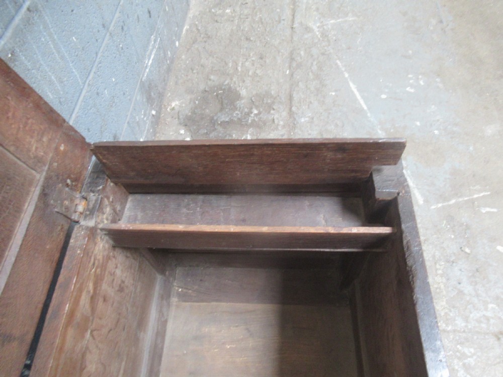 An 18th-century carved oak kist featuring twin front panels with diamond and rosette carvings beneath a lunette-carved top frieze. View V