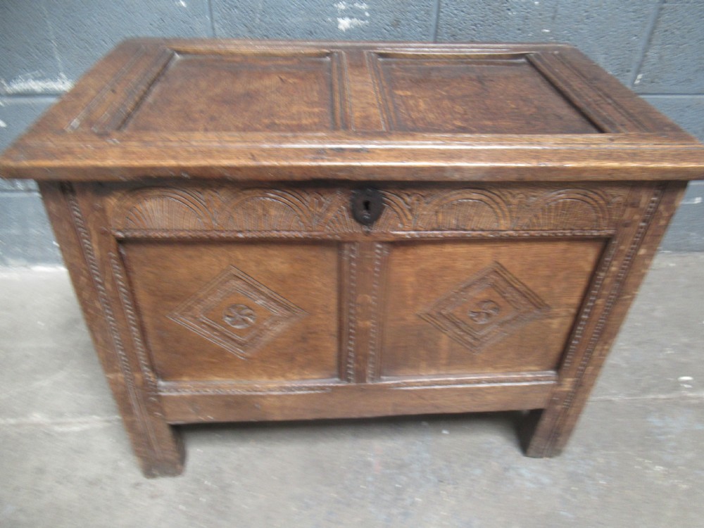 An 18th-century carved oak kist featuring twin front panels with diamond and rosette carvings beneath a lunette-carved top frieze. View X