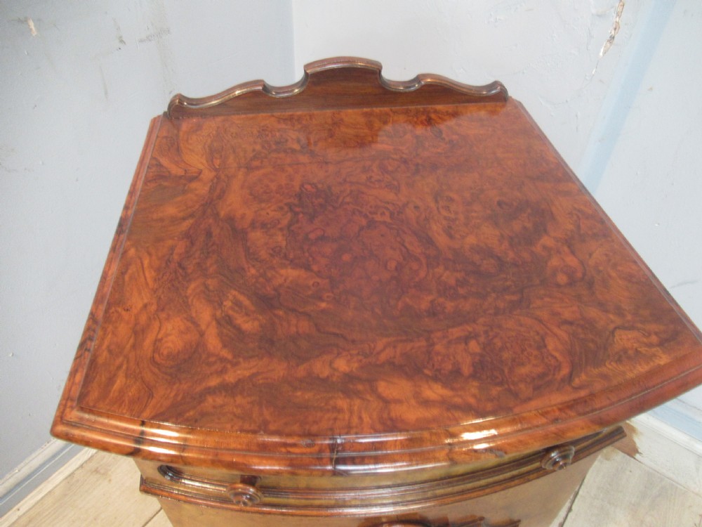 A Victorian burr walnut cabinet featuring a top drawer, a lower cupboard door with a carved shell motif, turned wooden knobs, and a shaped top upstand. View VII