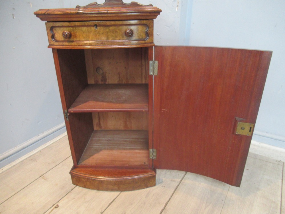 A Victorian burr walnut cabinet featuring a top drawer, a lower cupboard door with a carved shell motif, turned wooden knobs, and a shaped top upstand. View X