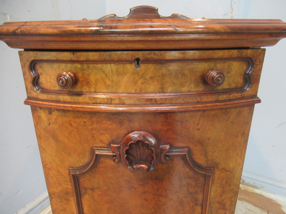 A Victorian burr walnut cabinet featuring a top drawer, a lower cupboard door with a carved shell motif, turned wooden knobs, and a shaped top upstand. View XI