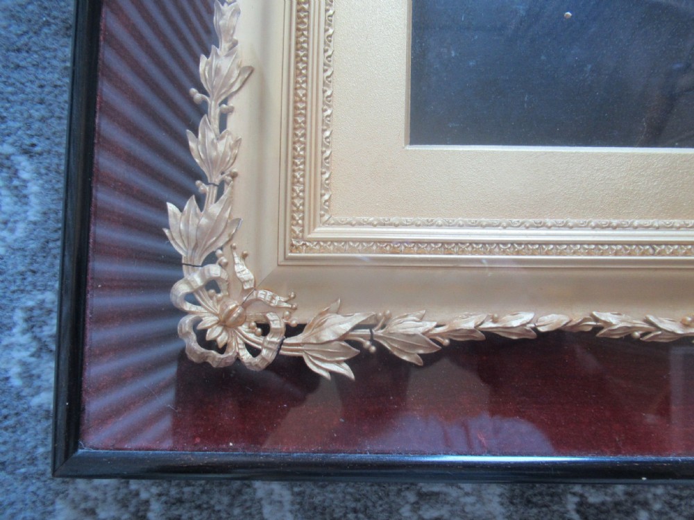 A Victorian monochrome photograph of a seated woman in a dark dress, housed in an ornate gold leaf inner border and a polished ebonised outer frame. View IV