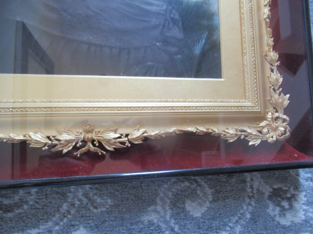 A Victorian monochrome photograph of a seated woman in a dark dress, housed in an ornate gold leaf inner border and a polished ebonised outer frame. View V