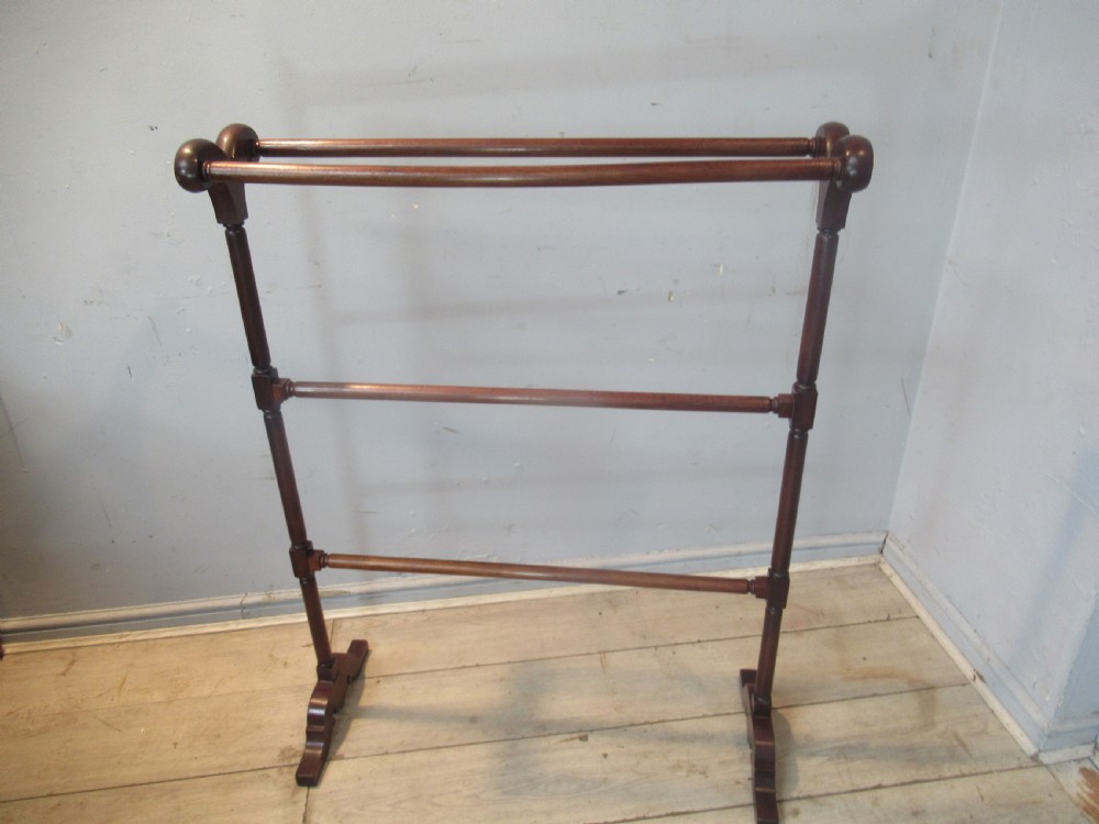 A freestanding dark mahogany Victorian towel rail featuring turned uprights, curved top finials, and shaped trestle feet. View II